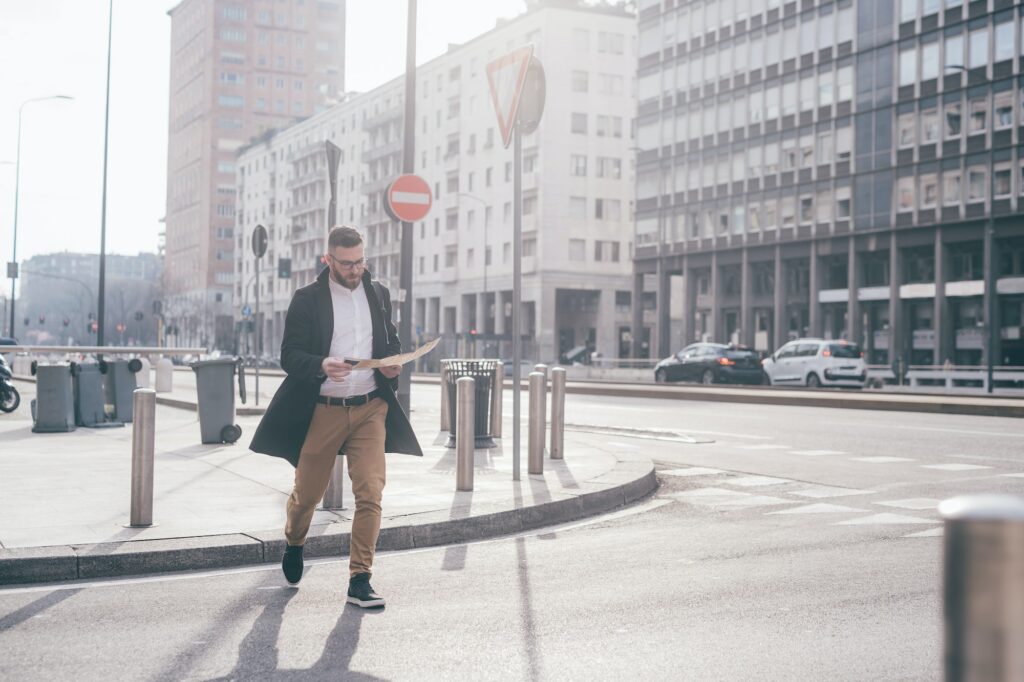 Young bearded caucasian traveller checking guide map and smartphone